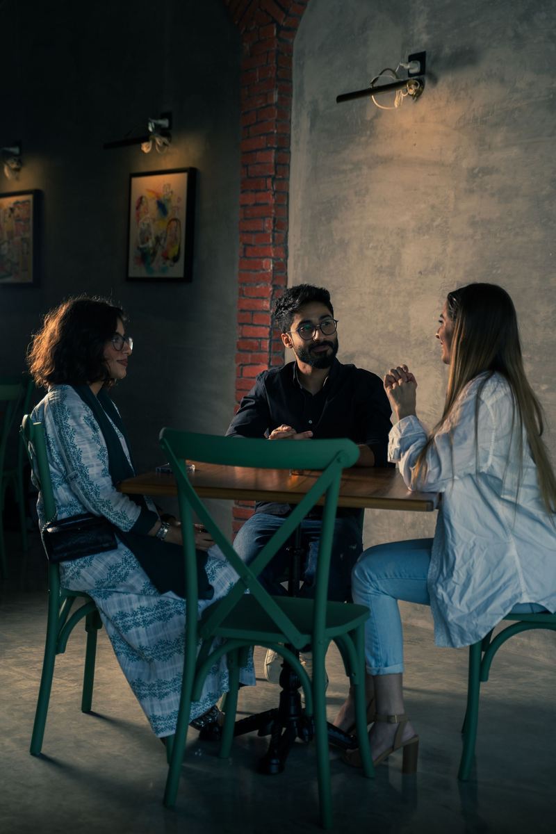 Three friends talking across a café table.