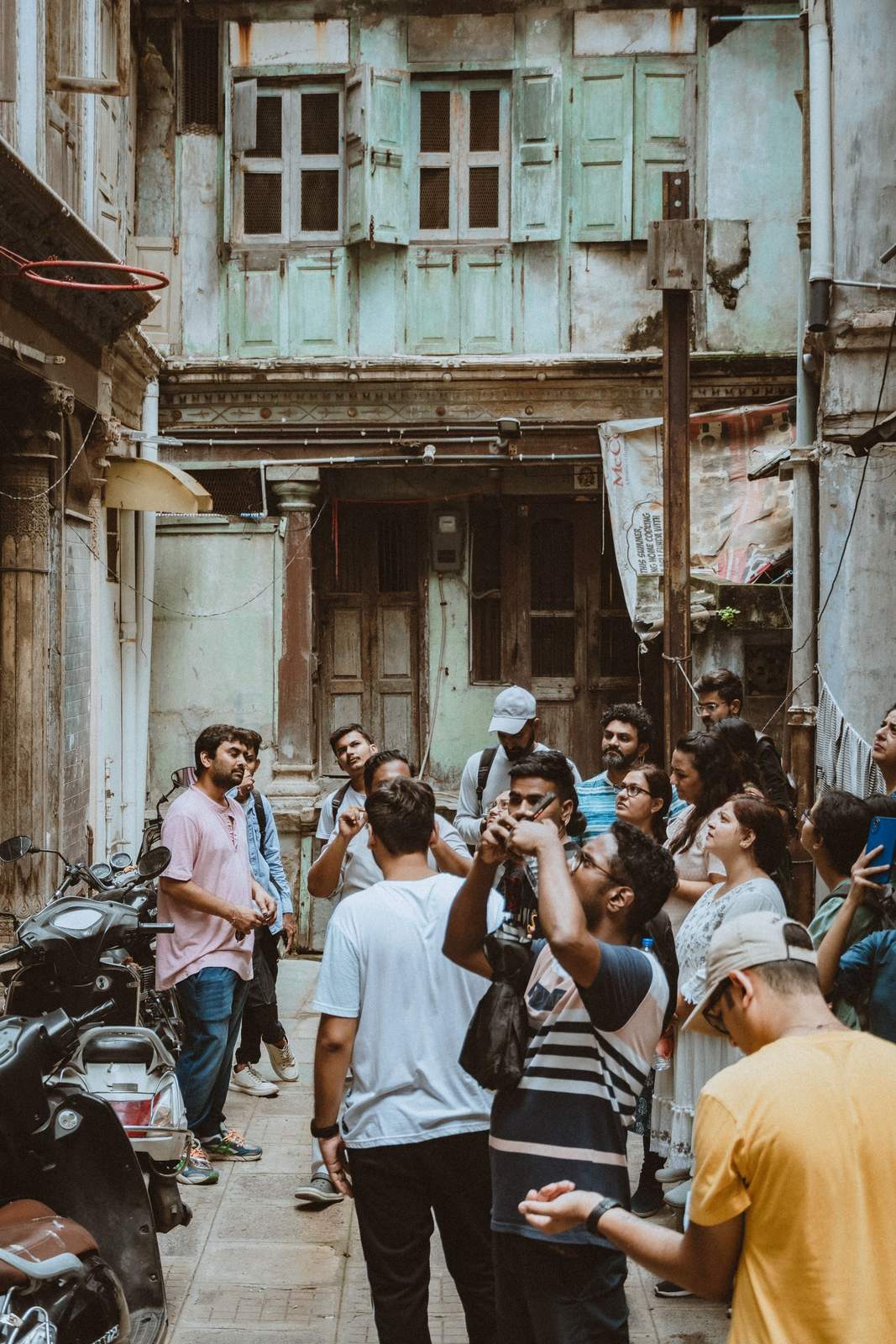 A group of people on a heritage walk, gathered in a busy old-city lane.