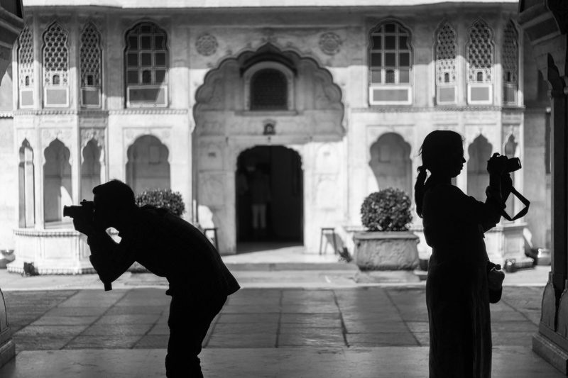 Two photographers in a heritage courtyard, each framing a shot.